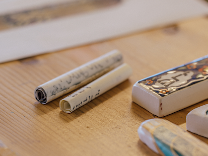 Wood table with rolled up paper and ceramic tablets