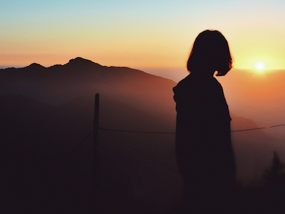 silhouette of women watching sunrise over mountains