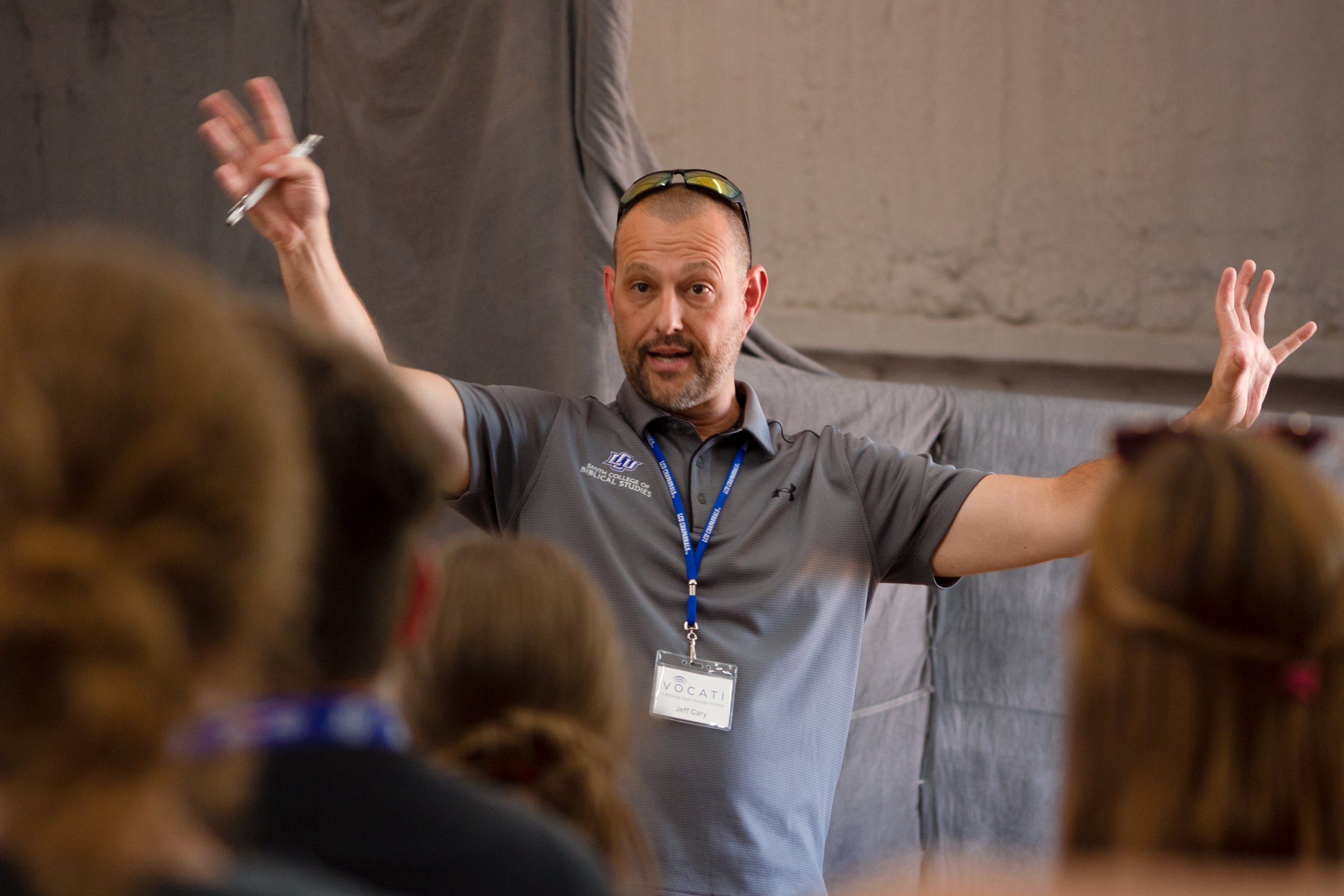 A teacher with his hands up in the air teaching a class