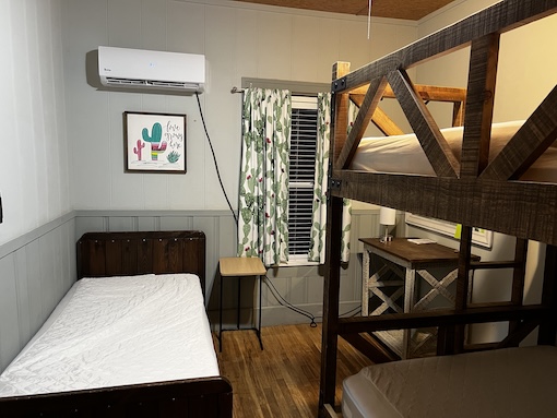 Housing room showing a twin bed and a bunk bed with cactus decor on the wall