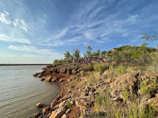 Group sitting on the edge of White River Lake during a morning devotional