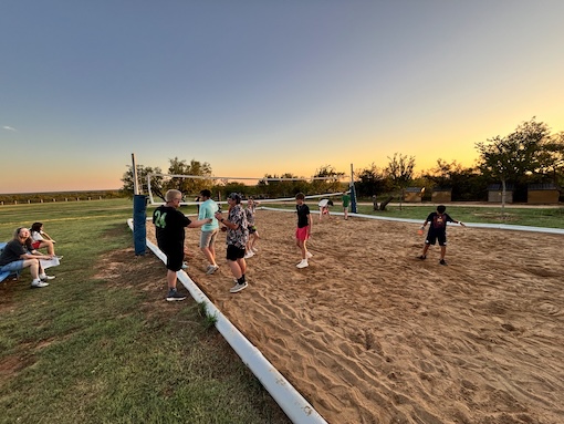  Campgrounds sand volleyball court with students playing and giving a high-five