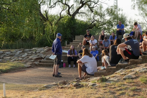 Group sitting at the campfire amphitheater in the morning, listening to someone speak