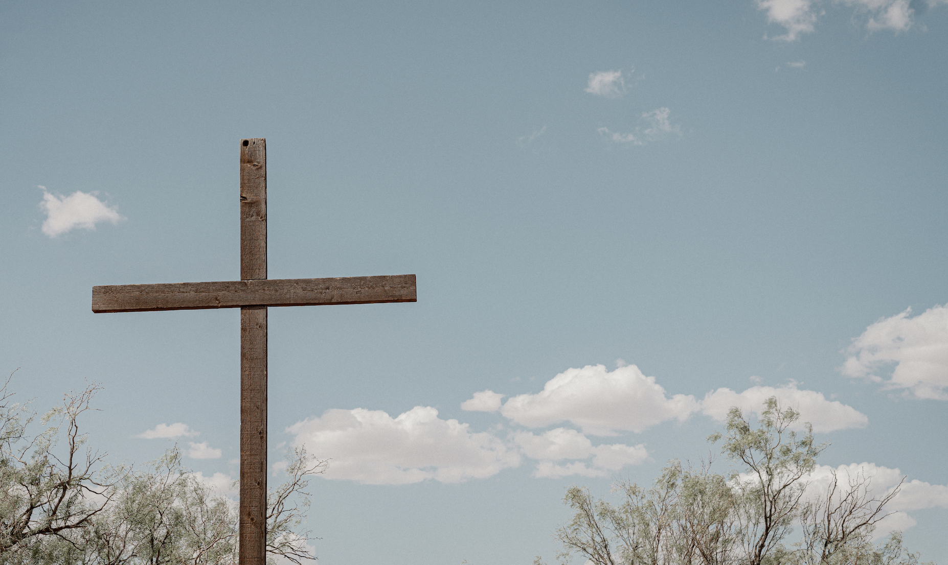 A blue sky with a wooden cross in the foreground